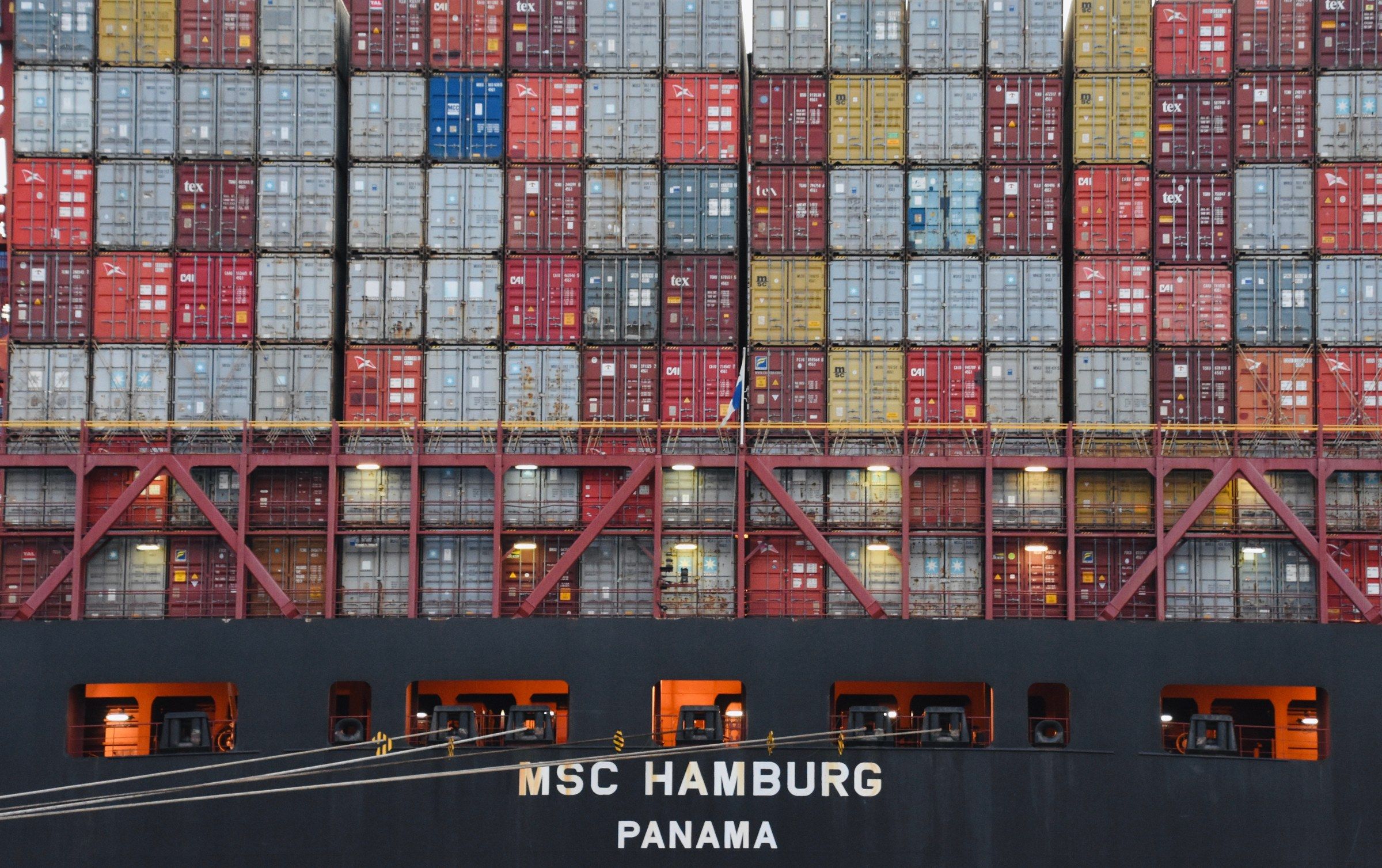 A container ship loaded with stacked shipping containers at a port at night.