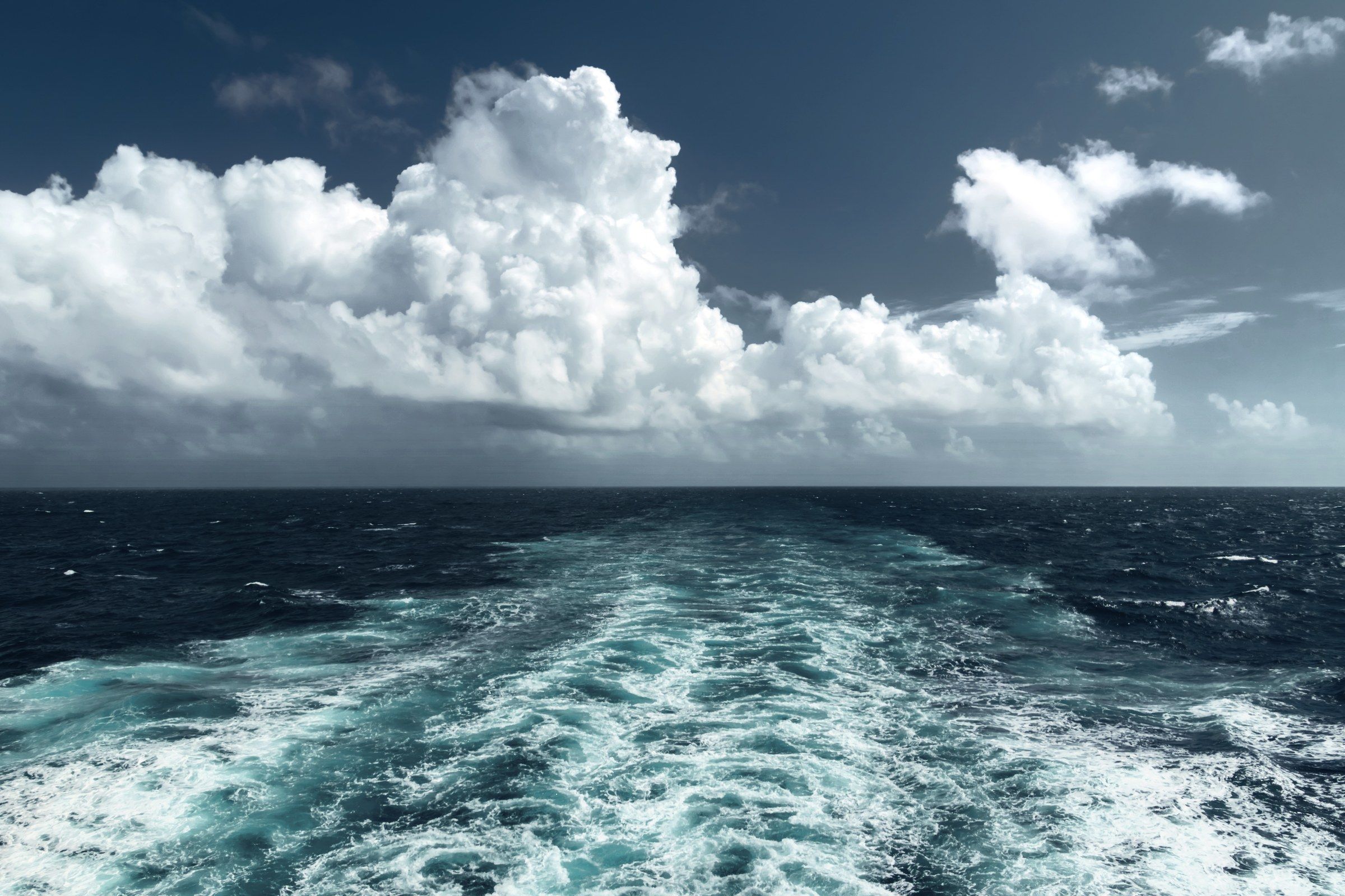 The churning wake trailing behind a ship at sea.