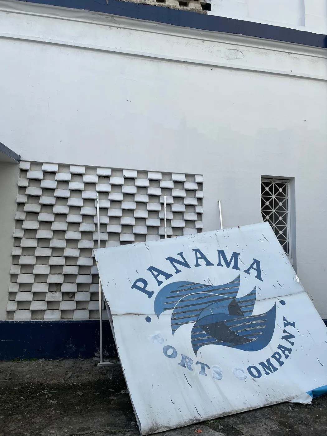 A weathered Panama Ports Company sign propped against a building.